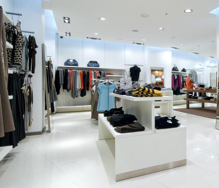 A retail store with white floors and clothing racks.