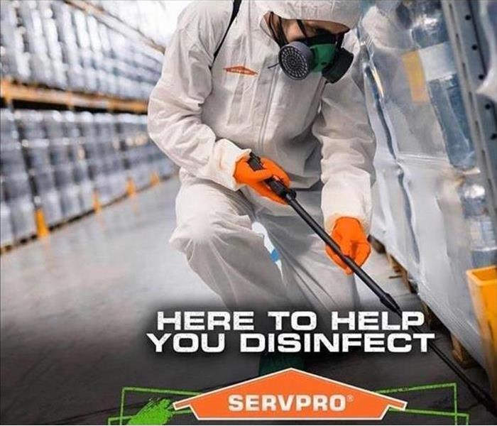 SERVPRO employee in hazmat suit decontaminates floor using sprayer.